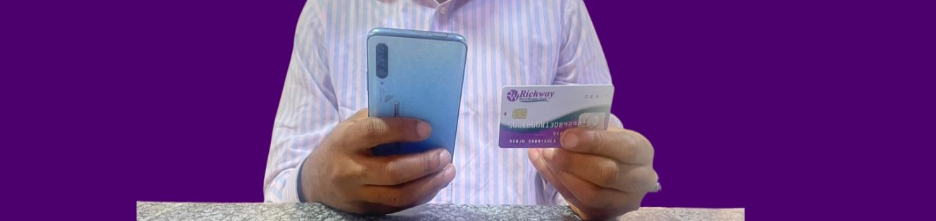 Person using a phone and credit card to make a purchase.